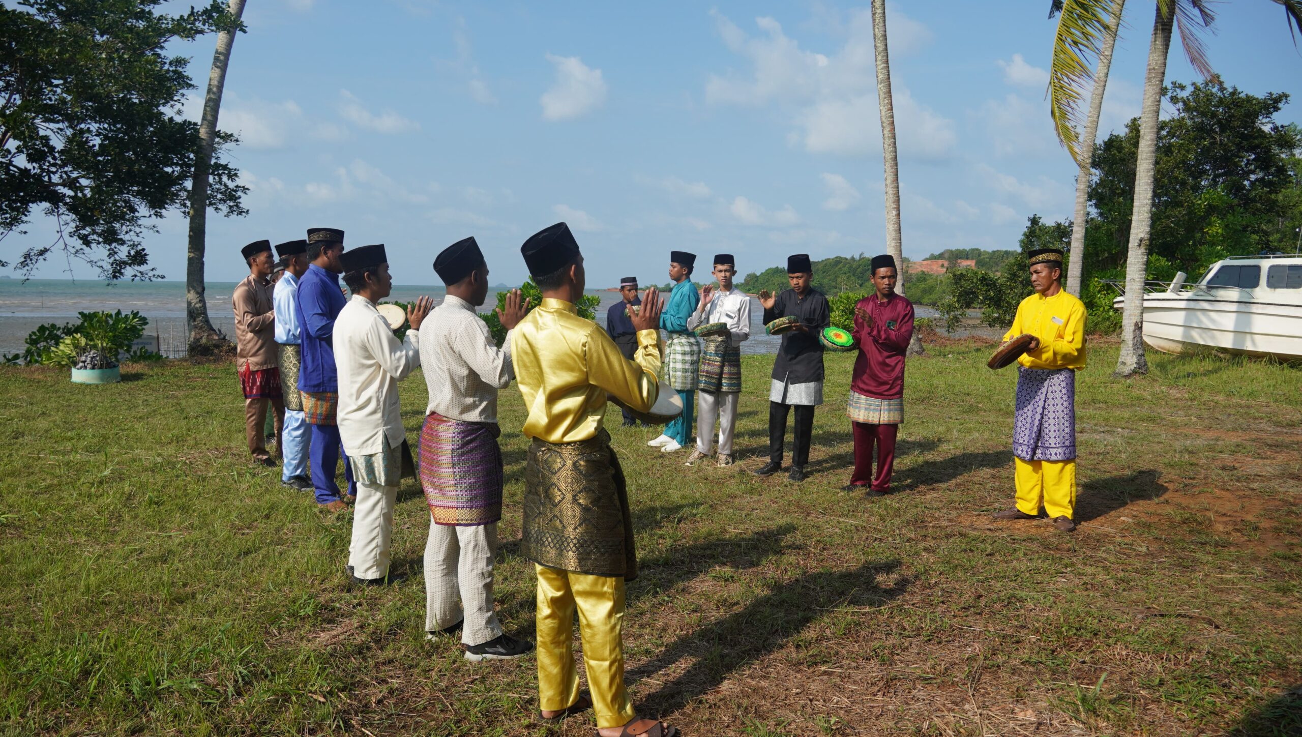Sekelompok pemuda berbaju adat Jawa warna-warni berbaris dalam 2 barisan dan saling berhadapan di atas tanah lapang dekat pesisir tampaknya berancang-ancang mempraktikkan tarian tradisional