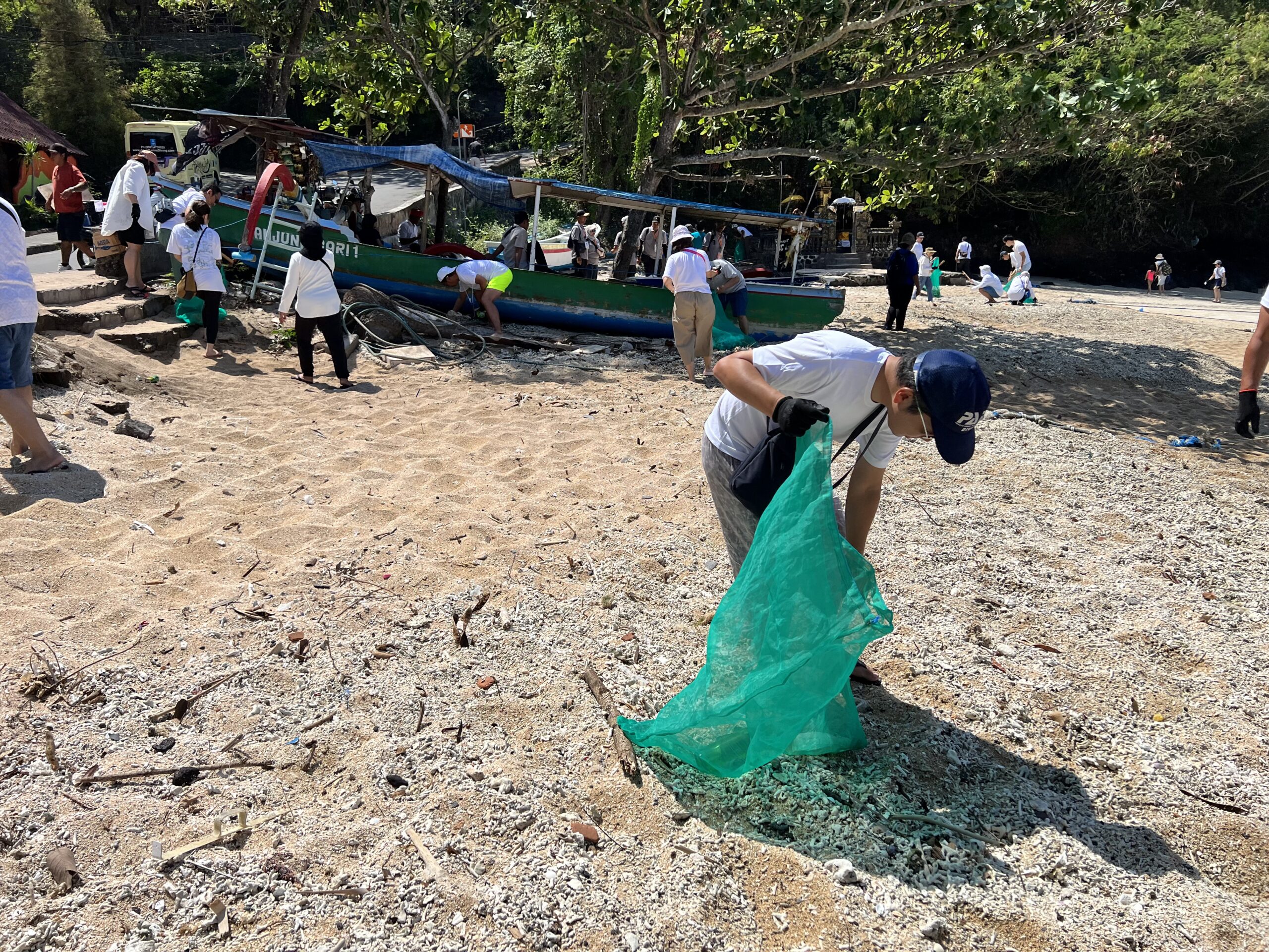 sekumpulan orang berbaju putih mengutip sampah pada acara beach cleanup