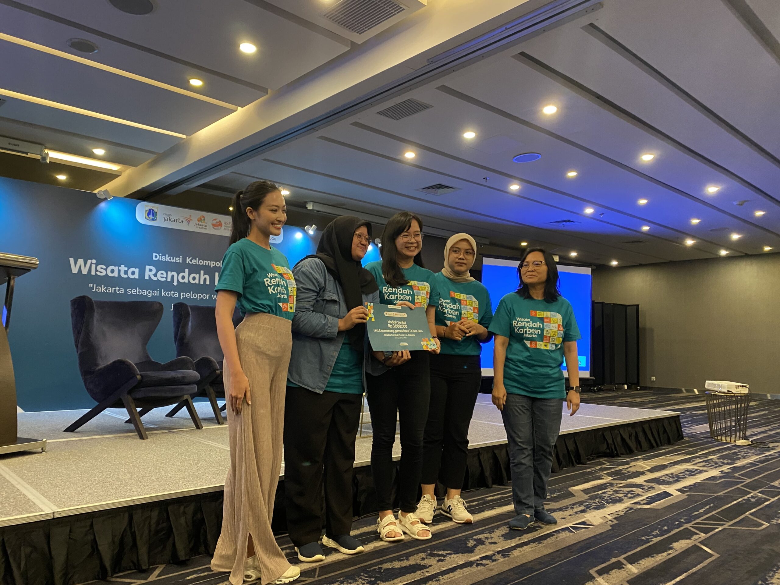 5 panelis acara Diskusi Kelompok Wisata Rendah Karbon berfoto di depang panggung sambil memegang kertas sertifikat semacam penghargaan