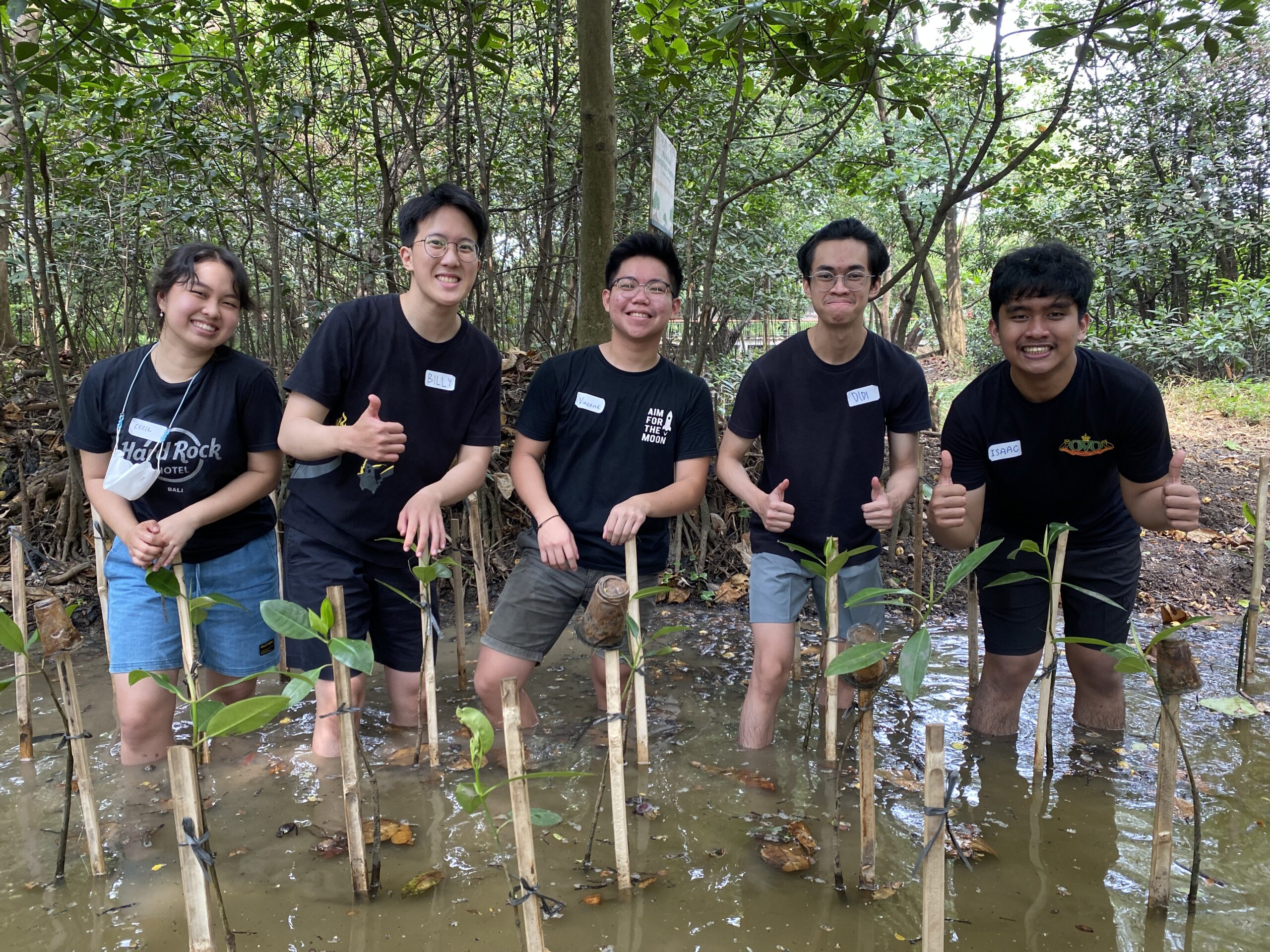 5 peserta tour penanaman mangrove mengacungkan jempol dengan ditutupi air lumpur setinggi setengah betis