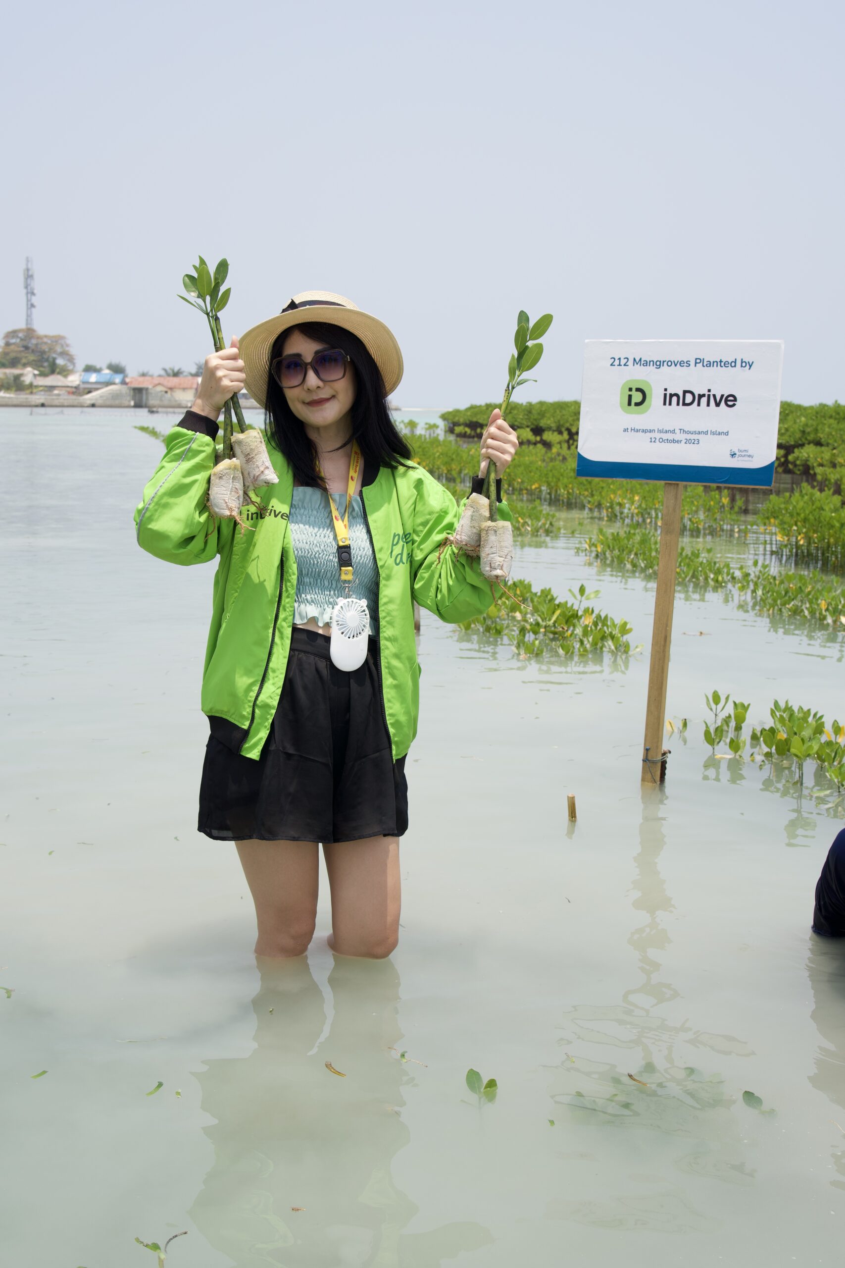 peserta wanita kegiatan CSR mangrove planting inDrive memang 4 batang benih mangrove di lokasi penanaman mangrove di Pulau Harapan